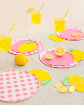 A vibrant summer table setting designed in San Francisco, featuring Neon Rose Pattern Plates - 7 inch from Oh Happy Day, yellow napkins with lemon slice accents, and refreshing lemonade in clear glasses, complete with striped.