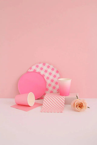 An assortment of pink-toned items, including Oh Happy Day's Neon Rose Pattern Plates - 7 inch, plain paper plate, cups, a striped gift box, and a pale rose, arranged against a soft pink background.