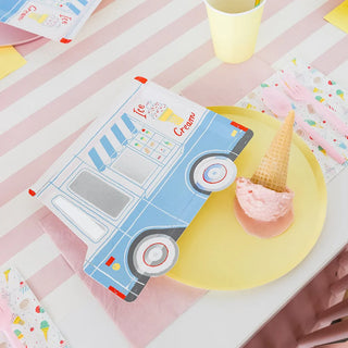 An Ice Cream Dreams Large Plate from Daydream Society with a pink ice cream scoop and cone sits on a pink and white striped tablecloth next to a folded napkin shaped like an ice cream truck, all part of the celebration decorations.