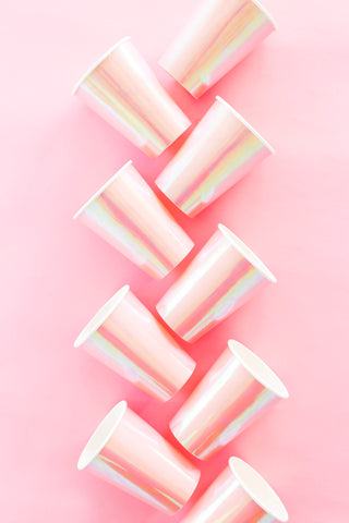 The Jollity & Co Posh Just Peachy Cups, eight in total, display iridescent pink hues and subtle foil details as they rest elegantly in two diagonal lines on a pink background.