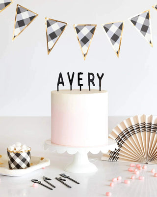 A black and white checkered letterboard cake topper with the name "avery" by My Mind’s Eye.