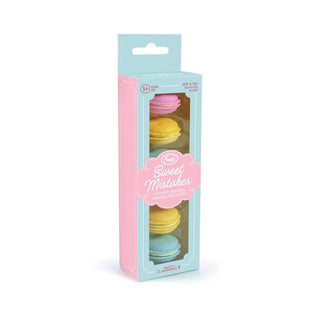 A box of six macaron erasers from Fred and Friends, scented like strawberries and available in pink, yellow, and blue, is packaged in pastel-colored cardboard with a transparent window and labeled "Macaron Erasers." These delightful BPA-free erasers make correcting errors a whimsical experience.