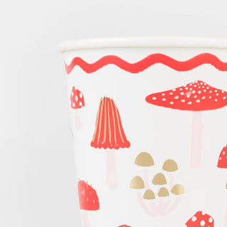 Meri Meri Merry Mushrooms Cups feature a holiday design with festive mushrooms in red and beige, accented by gold foil and wavy red lines at the top.