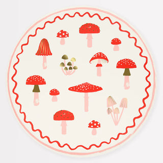 The Merry Mushrooms Dinner Plates by Meri Meri feature a circular illustration depicting various red and white mushrooms in different shapes and sizes on a light background, accentuated with a red wavy border and gold foil details.