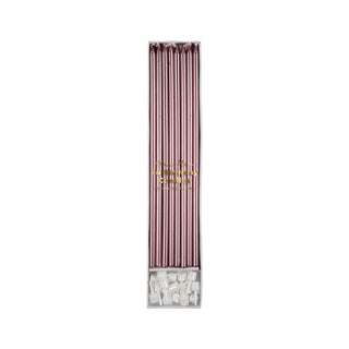 A box containing long, thin, Metallic Pink Candles by Meri Meri arranged vertically, with elegant white candle holders included at the bottom. Perfect for any birthday party.