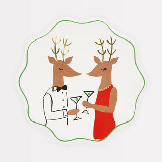 An illustration of two anthropomorphic deer dressed in formal attire, holding martini glasses and standing near festive tableware. The deer on the left wears a tuxedo, and the one on the right wears a red dress and pearl necklace, featured on Sprinkle BASH's Mr. & Mrs. Reindeer Side Plates.