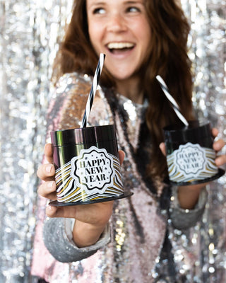 A woman holding two cups with Packed Party New Year's Eve Top Hat Novelty Sippers, a perfect party accessory for the New Year.