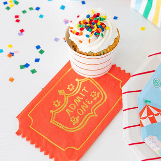 A cupcake with confetti and a ticket on a plate, perfect for circus parties featuring Off to the Fair Admit One Napkins by Daydream Society.