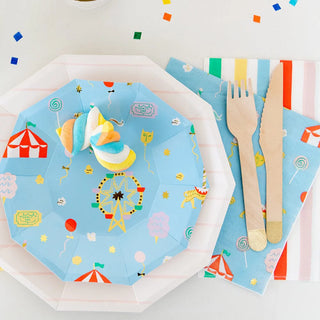 A carnival-inspired place setting featuring Off to the Fair Small Plates by Daydream Society, adorned with amusement park illustrations, a wooden fork and knife, a blue circus-themed napkin, and colorful marshmallows is perfect for your circus parties.