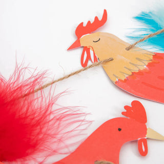 The Meri Meri On The Farm Large Garland, showcasing rooster shapes with vibrant feathers and linked by a brown twine, is perfect for decorating birthday parties.