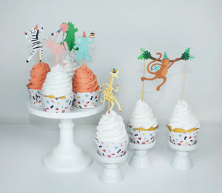 Six cupcakes with white and pink icing, adorned with Merrilulu's Party Animals - Cupcake Toppers & Wrappers, are displayed on a white stand and individual holders.