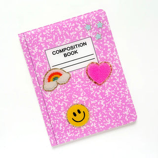 A Kailo Chic Pink Composition Notebook Tray with a speckled pattern is decorated with patches of a rainbow, a pink heart, a smiley face, and silver stars—perfect for back-to-school supplies.