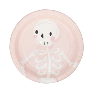 A round pink paper plate from the My Mind’s Eye Pink Monster Plate Set features a simple, cartoon-like skeleton drawing with a skull, ribcage, and arm bones—perfect for fun Halloween parties.