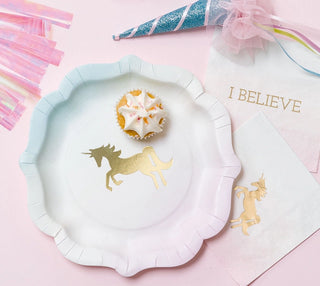 A cupcake with star-shaped decorations sits on a unicorn-themed paper plate, accompanied by Small Unicorn Napkins from Talking Tables emblazoned with "I BELIEVE" text and a festive unicorn horn party hat.