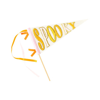 The "Spooky Felt Pennant" by My Mind’s Eye is a triangular white pennant displaying the word "SPOOKY" in gold letters. It is adorned with orange and pink ribbons and mounted on a stick, making it perfect as Halloween decor or a Halloween-themed banner.