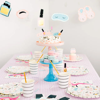 A colorful table set for a celebration with a pastel cake on a stand, macarons, striped paper cups with straws, plates with a fun design, and Daydream Society Sweet Dreams Large Napkins.