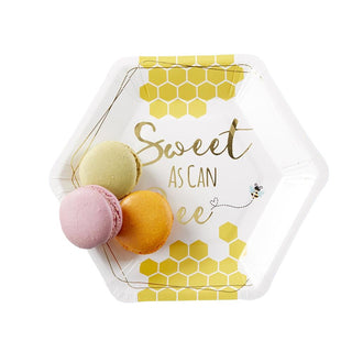 Hexagonal Kate Aspen Sweet as Can Bee Cocktail Plate with "Sweet as Can Bee" text and honeycomb pattern, holding three macarons (one green, one pink, one orange) on a light blue textured surface.