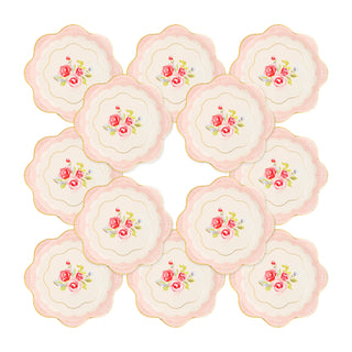 A collection of 12 floral-patterned, scalloped-edge paper plates arranged in a grid. These gorgeous Tea Party Scalloped Round Paper Plates by My Mind’s Eye feature pink roses on a white background with a pink border, adding an elegant touch that's perfect for any tea party.