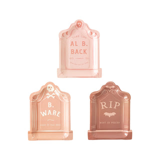 The Tombstone Plate Set by My Mind’s Eye includes three pink gravestone-shaped Halloween decorations with humorous text: "AL B. BACK - One bad trip for both," "B. WARE - Enter if you dare," and "RIP - Rest in Pieces." Perfect for adding a touch of fun to your Halloween party, they pair great with spooky treats!