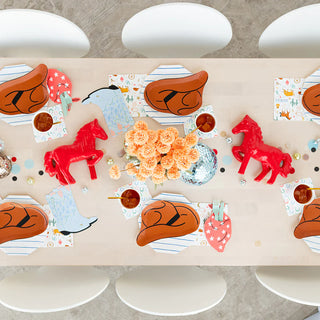 A table set up for a cowboy-themed birthday party, featuring Yeehaw Large Cowboy Hat Plates and decorations inspired by the rodeo by Daydream Society.