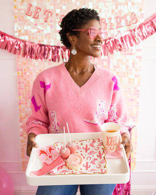 A woman in a pink sweater and heart-shaped sunglasses smiles while holding a tray with My Mind's Eye Bandana Paper Cocktail Napkins.