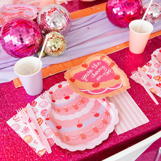 The romantically sweet collection from Jollity & Co features a pink-themed party table adorned with disco balls, cherry and cake-patterned die-cut plates, striped napkins, and cups. The "You're the Cherry On Top Dessert Plates" serve as a centerpiece, adding charm to this delightful setting.