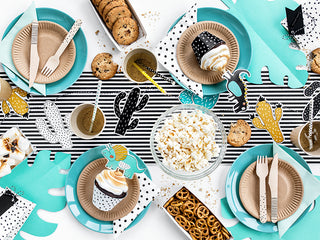 A table set for a party with teal plates, beige cutlery, cupcakes, cookies, popcorn, pretzels, and cactus-themed decorations on a black-and-white striped table runner is completed with a playful Cacti Garland by Party Deco for the perfect touch to your themed parties.