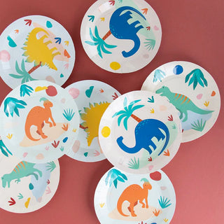 A collection of vibrant, My Little Day Dinosaur Jurassic Plates arranged artistically on a pink background, perfect for a festive children's birthday party.