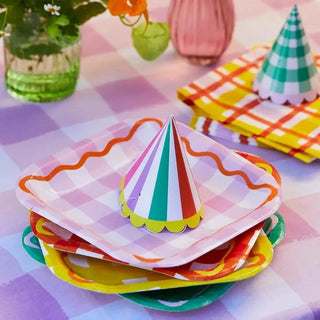 A colorful table setting with Everyone's Welcome Square Paper Plates and Talking Tables party hats.