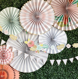 A collection of My Mind's Eye Garden Party fans hang gracefully on the vibrant green wall, perfect for elegant gatherings.