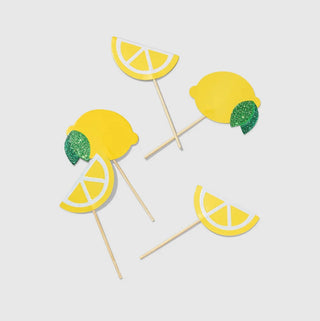 A group of Lemon Mini Toppers on sticks, with green glitter accents, on a white background by Coterie Party Supplies.