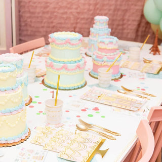 A table full of Let Them Eat Cake Large Cake Plates and balloons at a birthday party, with gold foil plates adding an elegant touch by Daydream Society.