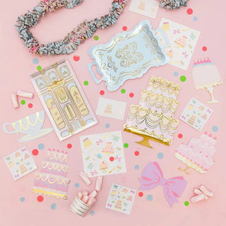 A pink background covered in a variety of items, including Let Them Eat Cake Large Cake Plates and Daydream Society plates.