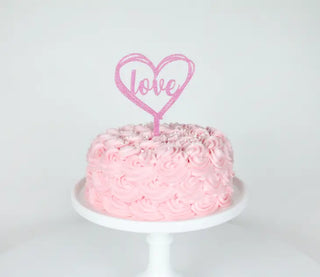 A pink Merrilulu cake topper with the word "love" on it, perfect for a wedding or Valentine's Day celebration.