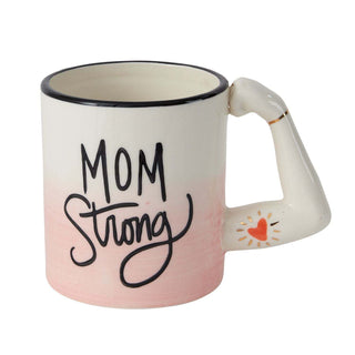 A handcrafted Mom Strong Ceramic Mug from Accent Decor with a pink-to-white gradient, featuring the hand-painted inscription "mom strong" in black cursive, with a heart detail on the handle. This unique item may include