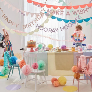 An eco-friendly birthday party with Rainbow Birthday Garlands and balloons adorning the table from Meri Meri.