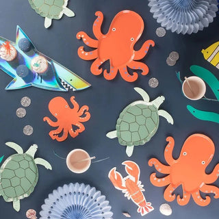 An octopus, a shark, and other sea creatures are on a table at an under-the-sea party with Meri Meri Turtle Plates.