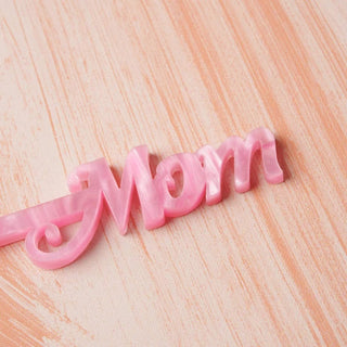 A Mother's Day Stir Stick Card - Opaque Pink with the word mom on it, perfect for cocktails. Designed by Em and Me Studio.
